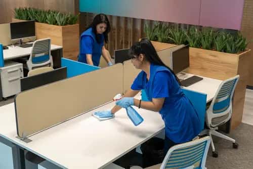 Office cleaning team wiping desks and surfaces